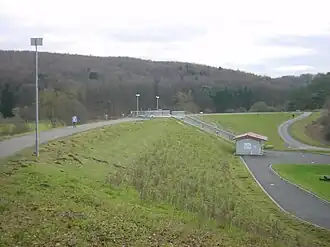Staudamm mit mittigem Auslassbauwerk und Betriebsgebäude; Blick vom Nordende des Damms nach Süden