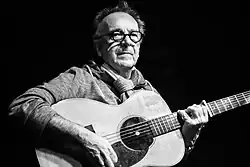 Soïg Sibéril während eines Fest-Noz in Poullaouen im Jahr 2016. Schwarz-Weiß-Aufnahme eines älteren Mannes mit Gitarre.