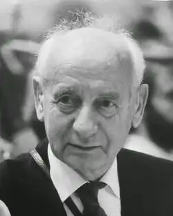 Älterer Mann von vorn ab Schulterblatt im dunklen Jackett, weißem Hemd und dunkler Krawatte in schwarzweiß.