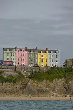 Ein Block sehr bunter Häuser auf Felsen oberhalb des Strands.