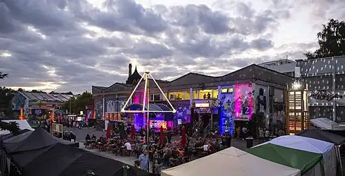 Der bunt beleuchtete Hof neben der KREA dient als Festivalplatz mit Bierbänken und vielen feiernden Menschen.