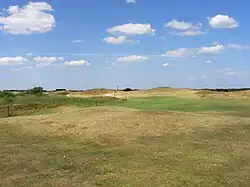 Hat sich der Spieler für einen Sicherheitsschlag entschieden, dann verbleibt eine unangenehm lange Distanz in das ebenfalls blind anzuspielende Grün, dessen genaue Lage hinter mehreren gestaffelten Dünen kaum einschätzbar ist.