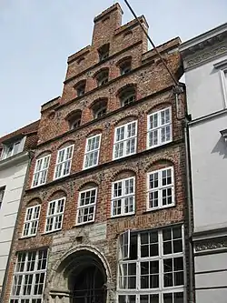 Mengstr. 64, 16. Jh., zwischen den Stilen, gotisches Kalk­stein­portal aus dem 13.&nbsp;Jh.