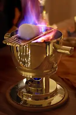 Brennender Rum auf Zuckerhut bei der Zubereitung einer Feuerzangenbowle