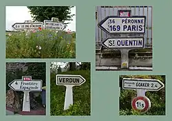 Zusammenstellung mehrerer Michelin-Wegweiser in Pfeilform im Schilderträger mit Standfuß