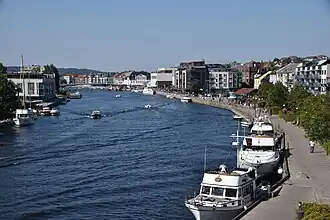 Foto eines lusses mit vielen Booten. An beiden Uferseiten befindet sich städtische Bebauung