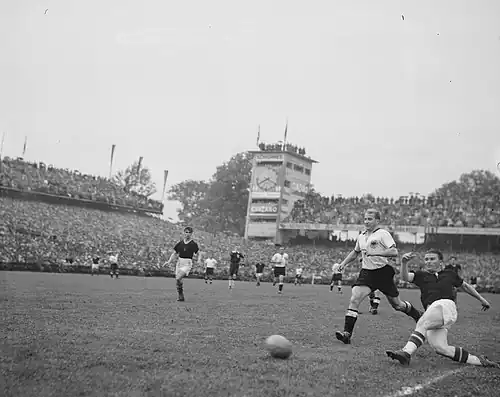 86. Minute: Mit letzter Kraft wirft sich Puskás in die Kopfballvorlage von Kocsis und erzielt das 3:3. SR Ling erkennt den Treffer aber nicht an. „Abseits“, zeigt LR Griffiths. Im Bild von links nach rechts (Akteure im Vordergrund): Kocsis (U), SR Ling, Jupp Posipal (D, rechts neben Ling), Werner Liebrich (D), Puskás (U)