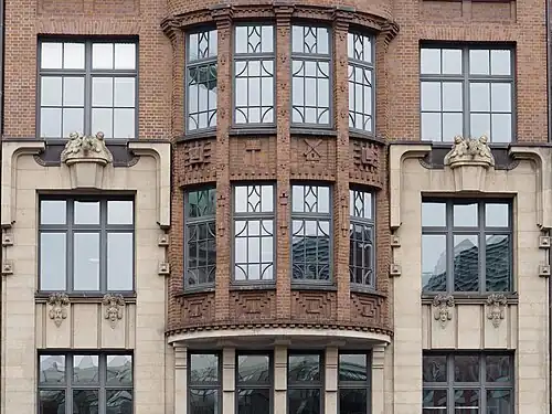 Erker mit Ziermauerwerk und seitliche Fenster mit Figurenschmuck