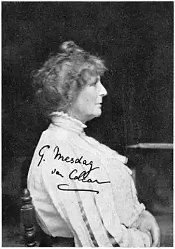 Schwarz-Weiß-Foto einer ernst blickenden, sitzenden Frau im Profil mit weißer, langärmeliger Bluse mit kleinem Stehkragen und hochgesteckten Haaren.