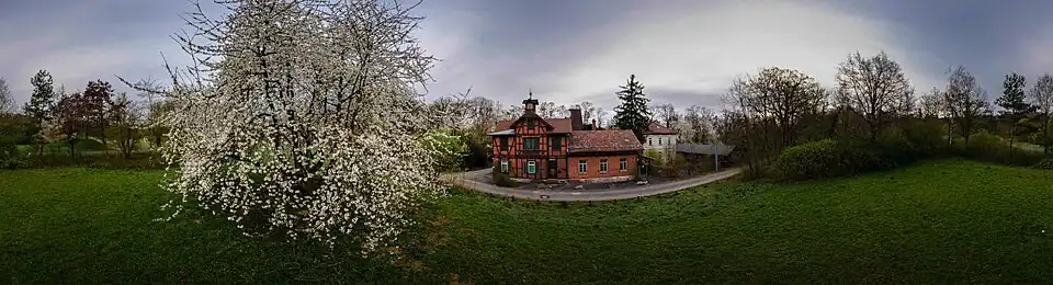 Das Panoramafoto zeigt das Gebäudeensemble des Garnisonsschützenhauses und den prachtvoll blühenden, weit ausladenden Kirschbaum in seiner unmittelbaren Nähe.
