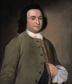 Der junge George Mason steht vor hellem Hintergrund mit einem roten Anzug.
