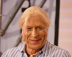 Porträtfoto einer Frau mit hellen Haaren, die frontal in die Kamera blickt und lächelt.