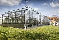 Im Vordergrund ist ein Gewächshaus von der Firma Strube in Schlanstedt zu sehen. Im Hintergrund befindet sich eines der Labor- und Büro-Gebäude.