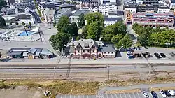 Drohnenfoto von einem Bahnhofsgebäude, dahinter städtische Bebauung