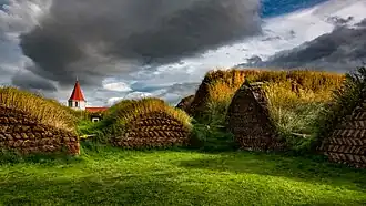 und enthält viele Hütten mit Wänden und Dächern aus Torfplaggen,
