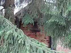 Glockenstuhl auf vier gusseisernen Stützen mit Glocke am Wirtschaftsgebäude des ehemaligen Schulgehöftes.