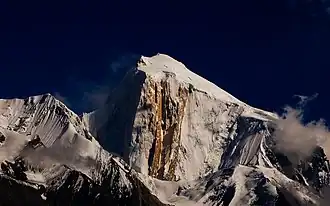 Die Nordwestseite des Spantik mit dem Golden Pillar an der Licht-Schatten-Grenze