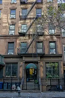 Ein Foto eines New Yorker Gebäudes mit 6 sichtbaren Stockwerken und einer Feuertreppe.