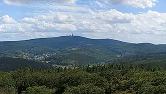Blick vom Aussichtsturm nach Süden zum Pfaffenrod im Vordergrund über der Ortschaft Schmitten, im Hintergrund Großer (mittig) und Kleiner Feldberg (rechts) über dem Schmittener Ortsteil Oberreifenberg.