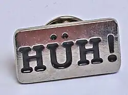 Manschettenknopf mit der Aufschrift HÜH!