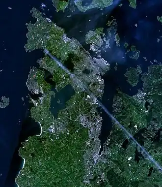 Satellitenbild einer durch Fjorde geformten Halbinsel mit dichterer Bebauung im Osten