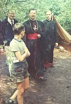 Heinrich Pachowiak auf einem Foto im Wald, umgeben von Jugendlichen mit der Katholischen Jugend Hannover auf einer Jugendfreizeit.