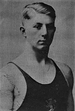 Schwarzweißfoto mit De Pauw im dunklen Badeanzug. Auf dem Anzug ist der Brabanter Löwe als Teil des belgischen Wappens erkennbar.