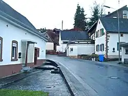 Hertlingshausen, Klosterhofstraße. In beide Häuser (links Nr. 5 und rechts Nr. 10) sind unter der Dachtraufe Spoliensteine vom Kloster in Zweitverwendung eingemauert (Fensterluken aus Sandstein, in Form griechischer Kreuze)