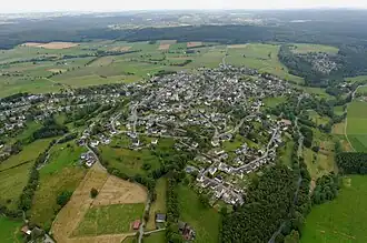 Das Ortszentrum von Hirschberg im Vordergrund ist Teil des Naturraums Kahlenbergsköpfe, dessen Hauptteil der bewaldete Querrücken im Bildhintergrund ist.