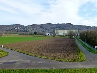 Blick von der Brücke der B&nbsp;38 über die neue Weschnitz ostwärts zum Hirschkopf: Hirschkopf (mittig rechts hinter der großen Halle), Saukopf (mittig hinter weißem Gebäude), Nächstenbach (Weinheim) (am Hang mittig links); dahinter links oberhalb der Weinheimer Kopf