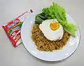 Zubereitetes Indomie Mie Goreng mit Ei und Salat als Beilage