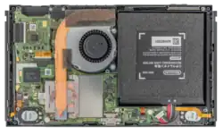 Das Foto zeigt eine aufgeschraubte Nintendo Switch mit Batterie (rechts) und Mainboard, Lüfter und Heatpipe (mitte-links)