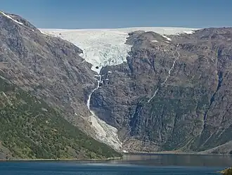 Oben der Isfjordjøkelen, ein Teilgletscher des Øksfjordjøkelen, unten der Gletscher Nerisen, ein sogenannter „regenerierter Gletscher“, der von den Lawinen des Isfjordjøkelen gespeist wird. Das Eis der Gletscher wurde bis 1949 von den Fischern und Händlern zu Kühlung des Fangs genutzt.[1]