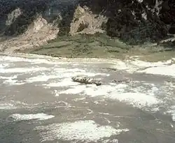 Isla Mocha: Nach dem Auf­tref­fen des Tsunamis ist ein Schiff auf Grund gelaufen. An der Steilküste sind zahl­reiche Erdrutsche erkennbar.