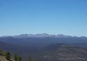 Ein großer, sanft geneigter Berg ragt an einem klaren Tag über die umgebende Landschaft.