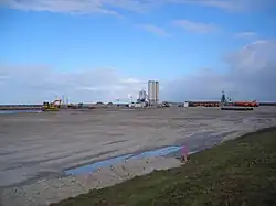 Oktober 2009: Auf dem bis knapp unterhalb der Deichkante aufgespülten Gelände steht ein Betonwerk. Die vor dem Deich verlaufende Straße ist überschüttet. (Vgl. Zustand Mai 2008)