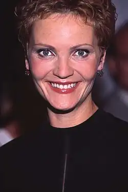Joan Allen mit einem breiten Lächeln trägt schwarze Kleidung. Der Hintergrund ist dunkel und es sind einige unscharfe Figuren sichtbar. Sie hat kurze, lockige Haare. Das Foto wurde 2000 bei den Toronto International Film Festival aufgenommen.