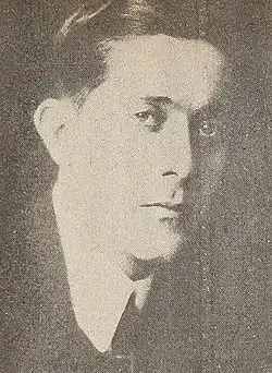 Mann im mittleren Alter von seitlich vorn und ab Schulterblatt im dunklen Jackett, weißem Hemd und dunkler Krawatte nach rechts schauend in schwarzweiß.