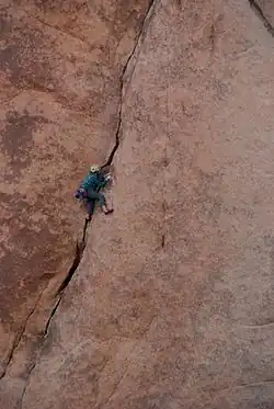 steile Wand mit einem Riss, in dem ein Kletterer steckt