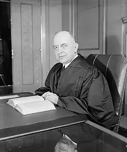 Schwarzweiß-Foto (Halbfigur) von Reed am Tisch sitzend mit aufgeschlagenem Buch