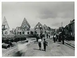 Die Käferstraße, etwa von der Kreuzung mit der Wöhrdenstraße bzw. Wasserstraße aus. Links das Anwesen Marie Engeßer, der Brandherd. Daneben, Bildmitte, die Ruine der Restauration Kuttruff. Ganz hinten rechts das Amtsgefängnis mit dem markanten Turm.