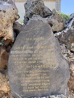 Poliertes Steindenkmal in einer Mauer zur Erinnerung an die Opfer des Aufstands von 1821 und die Opfer der Kriege.