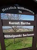 Blick durch die Werbe- und Begrüßungstafel nach Kurort Hartha