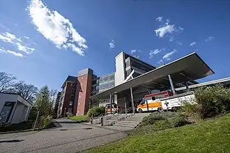 Man sieht den Eingang der Vestischen Kinder- und Jugendklinik Datteln in der Sonne. Vor der Klinik stehen zwei Rettungswagen.