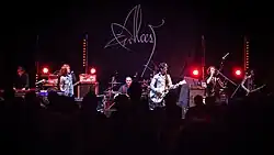 Band bei einem Bühnenauftritt von vorne in Farbe.