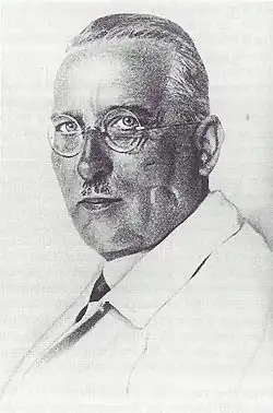 Eine schwarz-weiß Fotografie zeigt Biesalski im Porträt. Er hat einen Oberlippenbart, ähnlich wie Hitler ihn trug, kurzes Haar und trägt eine runde Brille