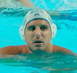 Mourikis ist im Wasser, er trägt eine weiße Kopfbedeckung.