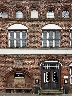 Südgiebel mit barocker Eingangstür, Sitznische und Wappentafel