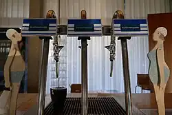 Das Foto zeigt die großzügig gebaute Marmortheke im Trinkpavillon mit zwei Wasserhähnen der Kurfürstenquelle und einem Wasserhahn des öffentlichen Wassers der Wahnbachtalsperre.