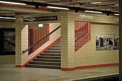 Treppe am westlichen Bahnsteig in Fahrtrichtung Friedrichstraße, 2023. Der über der Treppe angebrachte Wegweiser wies auch „Zum Stettiner Bahnhof“ hin und wurde nach dessen Schließung mit dem Wort „Ausgang“ übermalt.
